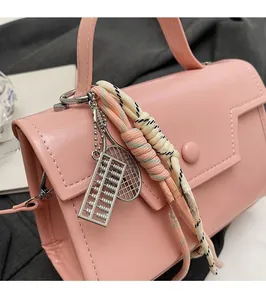 Pink leather handbag detail featuring unique abacus and tennis racket charms with rope trim