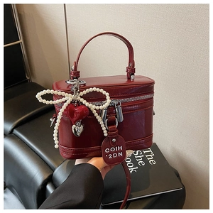Detail view of burgundy leather box bag with pearl bow and red heart charms