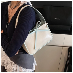 Vue détaillée du sac seau blanc crème et bleu clair avec nœud porté par un mannequin