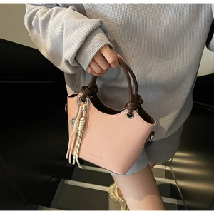 Détail d'un sac seau rose avec poignées marron et lettrage élégant FASHION & YM