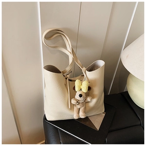 Detail of minimalist beige tote bag with fine leather texture and cute plush puppy charm
