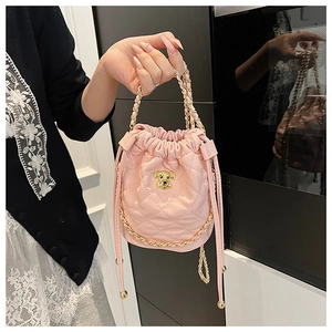 Gros plan d'un sac seau en cuir matelassé rose avec chaîne dorée et breloque chien