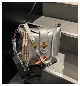 Detailed shot of silver bucket bag with gold clasp and tennis racket charm accessory