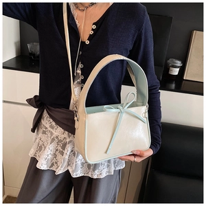Détail du sac seau en cuir verni beige clair avec un nœud bleu et une finition brillante