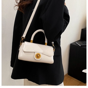 Détail du sac à main blanc en cuir verni avec fermoir tournant doré et bandoulière fine