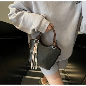Détail du sac seau vert olive avec poignée tressée et accessoire de charme contrasté