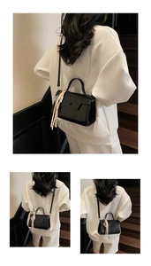 Detail view of black glossy leather handbag with shoulder strap and decorative silk scarf