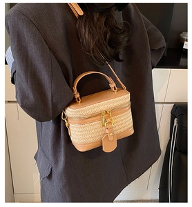 Detail of hand-woven straw and brown leather crossbody bag with adjustable strap