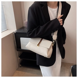 Model view of a beige pebbled leather crossbody bag with wide strap and gold buckle detail