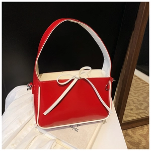 Détail d'un sac seau en cuir verni rouge vif avec nœud élégant et bordures blanches fines