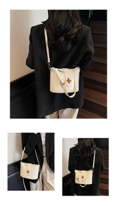 Detail of cream glossy bucket bag featuring gold metal cross-twist lock and adjustable strap