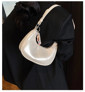 Detail of white glossy oil wax leather half-moon bag with pearls on a black suit