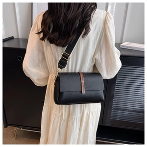 Detail view of the black pebbled leather crossbody bag with brown trim and wide strap