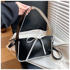 Détail d'un sac seau bicolore noir et blanc avec nœud en cuir blanc et large poignée