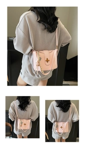 Close-up of pink leather handbag with metallic turn-lock clasp and stylish woven charm