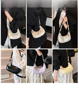 Detail view of the half-moon shoulder bag in four colors with adjustable straps and charms