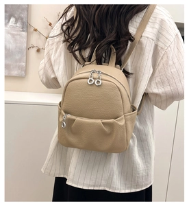 Close-up of litchi texture beige backpack featuring shiny silver zippers and front pocket