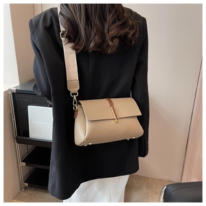 Chic beige crossbody bag with wide strap and pebble texture shown on a female model