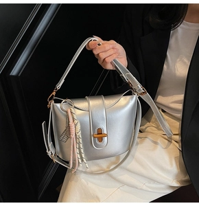 Close-up of silver crossbody bag with gold twist lock and woven tassel detail