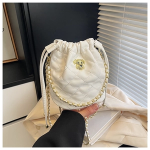 Détail du sac seau matelassé blanc avec ornement de chien doré et bandoulière en chaîne