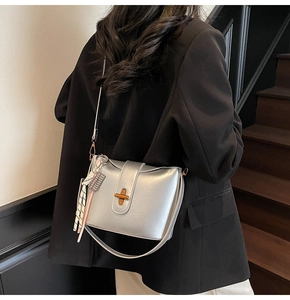 Detailed view of silver glossy handbag with golden cross lock and silk scarf accessory