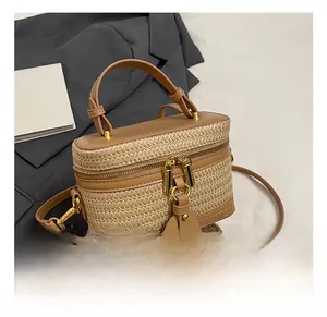 Close-up of woven straw box bag with brown leather handles and vintage metal hardware