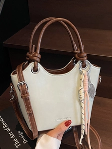 Sac seau vert minimaliste avec poignée tressée et pendentif raquette sur marches en bois