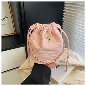 Détail du sac seau matelassé rose avec logo chien doré et bandoulière en chaîne