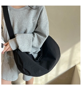 Detail of black crescent hobo bag made of lightweight nylon with natural drapes