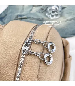Detail of lychee textured leather backpack featuring shiny silver metal double zippers