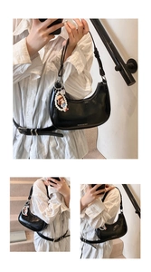 Detail view of black glossy faux leather hobo bag with a decorative pearl doll charm
