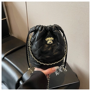Détail du sac seau noir matelassé avec emblème de chien doré et bandoulière chaîne