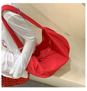Detail of red large nylon tote bag with wide shoulder strap and silver metal buckle