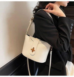 Detail of minimalist white oil wax leather crossbody bag with gold cross buckle on model