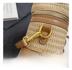 Detail of straw woven box bag featuring brown leather trim and golden metal hooks