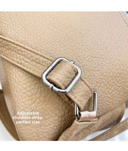 Detail of adjustable shoulder strap and silver metal buckle on beige lychee grain leather bag