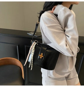 Detail of black oil wax leather crossbody bag with gold buckle and floral silk scarf