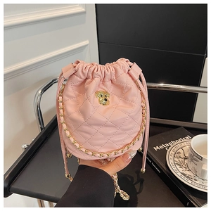 Détail du sac seau matelassé rose avec emblème de chien doré et bandoulière chaîne
