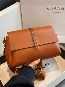 Brown lychee leather crossbody bag with wide shoulder strap and gold hardware accents