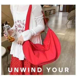 Detailed view of large red crescent hobo bag made of nylon worn by model in cafe