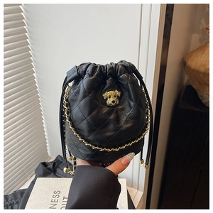 Détail du sac seau noir matelassé avec breloque chien dorée et bandoulière en chaîne