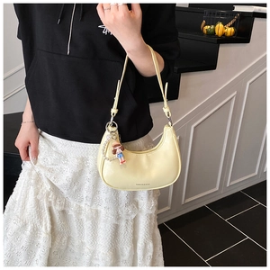 Détail du sac hobo croissant jaune avec breloque poupée et chaîne de perles décorative