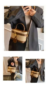Detail view of woven straw box bag featuring brown leather trim and golden hardware