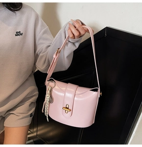 Close-up of pink leather handbag with gold metal clasp and woven cord charm detail