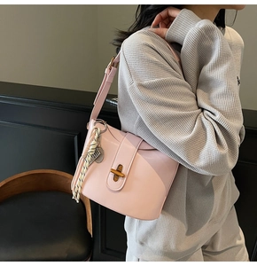 Detail of light pink faux leather bag with golden twist lock and colorful rope charm