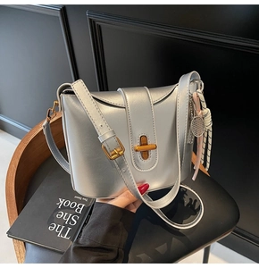 Detail of silver oil wax leather bucket bag with gold twist lock and tennis racket charm