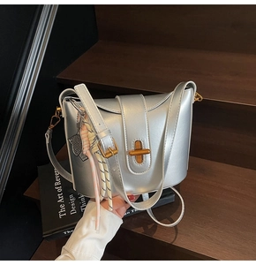 Detail of silver metallic bucket bag with golden twist lock and tennis racket charm
