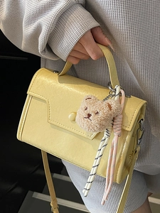 Minimalist light yellow crossbody bag with top handle and cute plush bear charm accessory