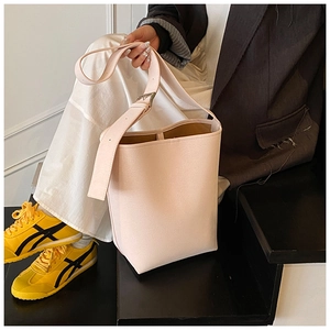 Détail du sac seau en cuir rose clair avec large bandoulière réglable et boucle en métal