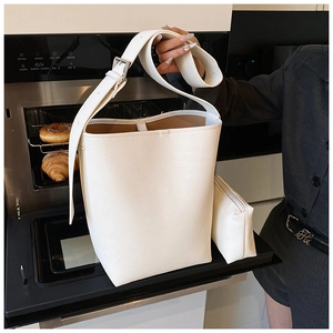 Détail d'un sac seau en cuir grainé blanc avec pochette assortie et large bandoulière chic